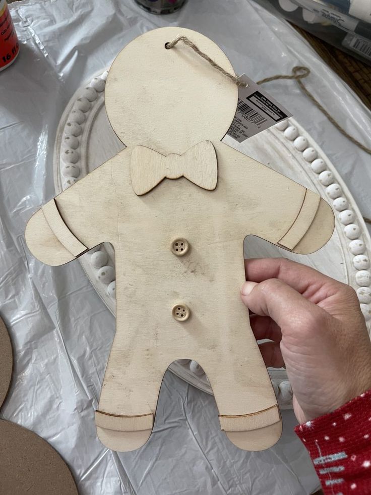 a person holding a wooden cut out of a man's body on top of a table