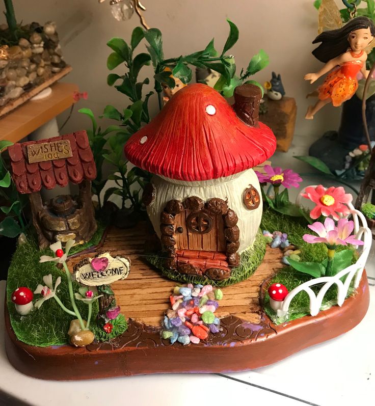 a mushroom house is surrounded by flowers and other small figurines in the background