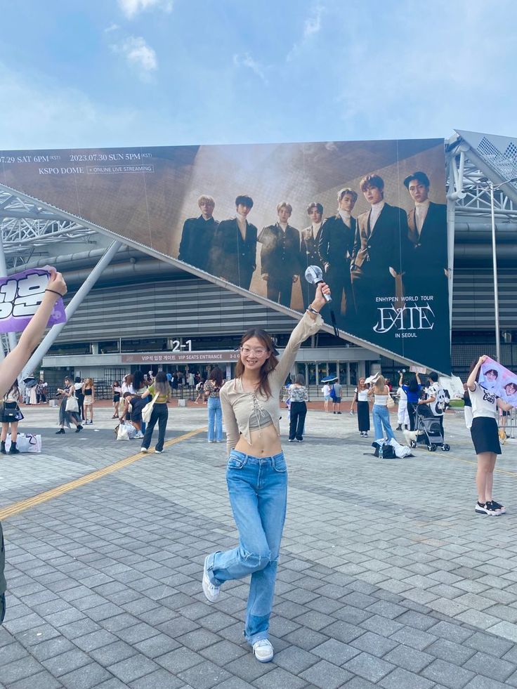 two women holding up their arms in front of a large poster on the side of a building