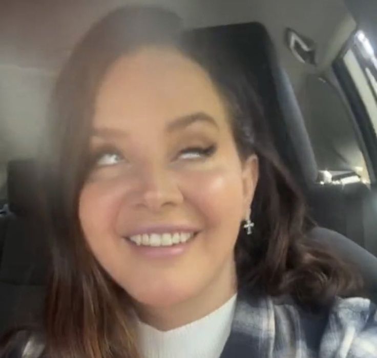 a woman sitting in the back seat of a car with her eyes open and smiling