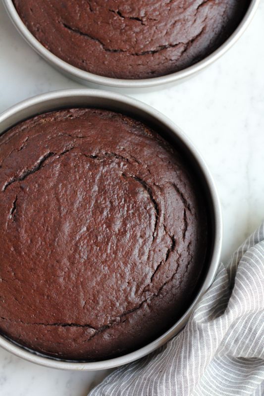 two chocolate cakes sitting in pans on top of a counter