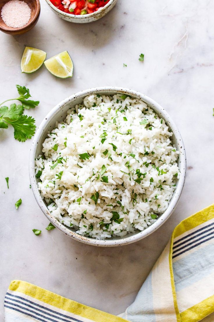 a bowl filled with rice and garnished with cilantro next to two bowls of salsa