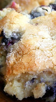 a close up of a blueberry cobbler on a wooden table with one piece cut out