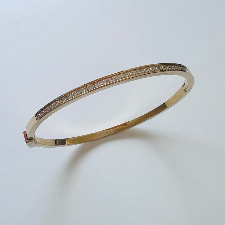 Durable and stylish, our waterproof bracelet is crafted for both functionality and fashion. Perfect for any occasion, it's the ideal accessory for those who appreciate durability and timeless elegance. Perfect for the minimalist and a beautiful piece to layer with. - 18K gold plated / stainless steel - Waterproof technology - Bangle opens and measures 56mm inner diameter. - 3mm in width. - Cubic Zirconia - Reversible Elegant Everyday Gold-tone Bangle, Gold Stainless Steel Bangle Bracelet, Chic Gold Stainless Steel Bracelets, Minimalist Gold-tone Bangle Bracelets, Minimalist Gold-tone Bangle Bracelet, Gold Stainless Steel Bangle, Tarnish Resistant, Tarnish Resistant Stainless Steel Gold Bangle, Timeless Stainless Steel Tarnish-resistant Bracelets, Yellow Gold Stainless Steel Bracelets