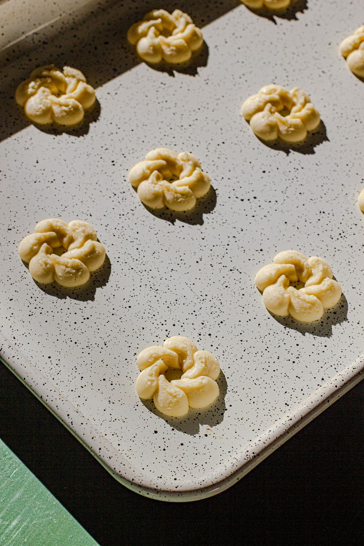 twelve uncooked doughnuts on a baking sheet