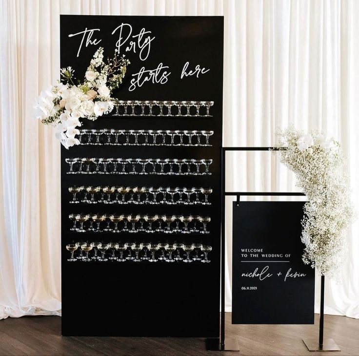 a black and white wedding sign with flowers on it next to a display for bracelets