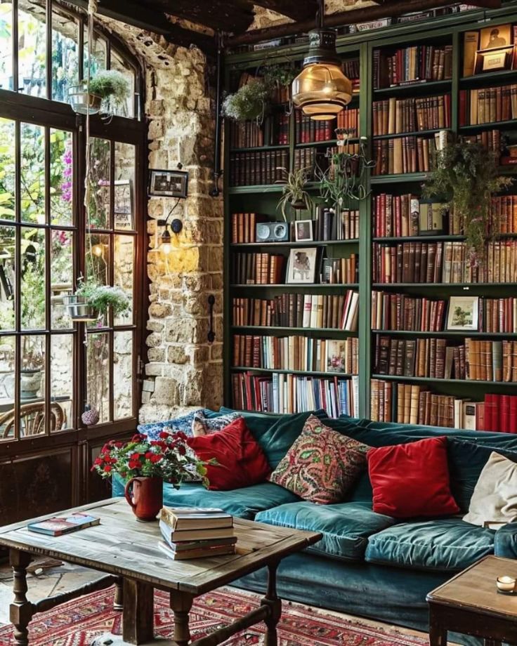 a living room filled with lots of books on top of a book shelf next to a window