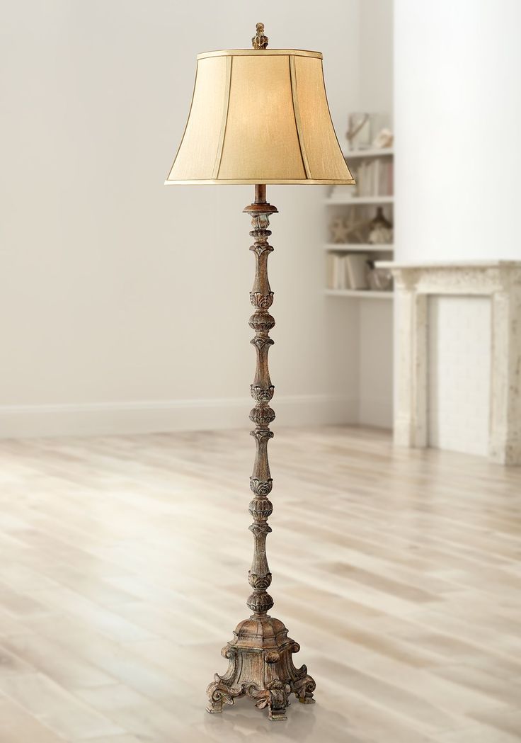 a floor lamp with a beige shade on it's side in a living room