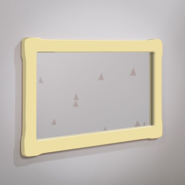 a yellow framed mirror hanging on the wall next to a white wall with small triangles