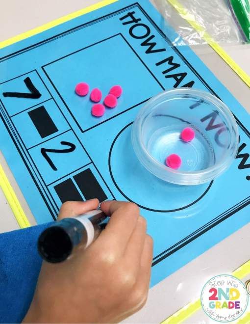 a person writing on a blue board with pink and black balls in front of it