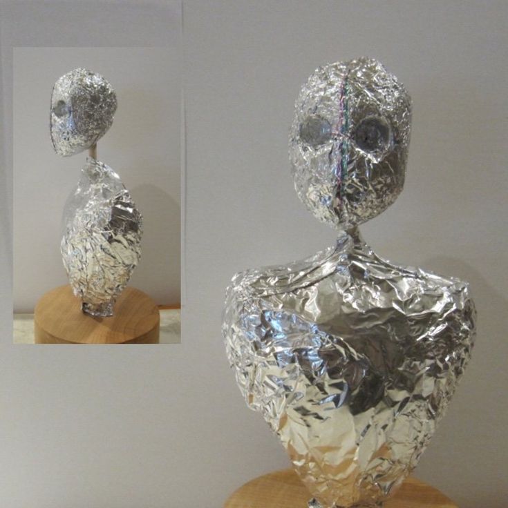 a silver sculpture sitting on top of a wooden stand