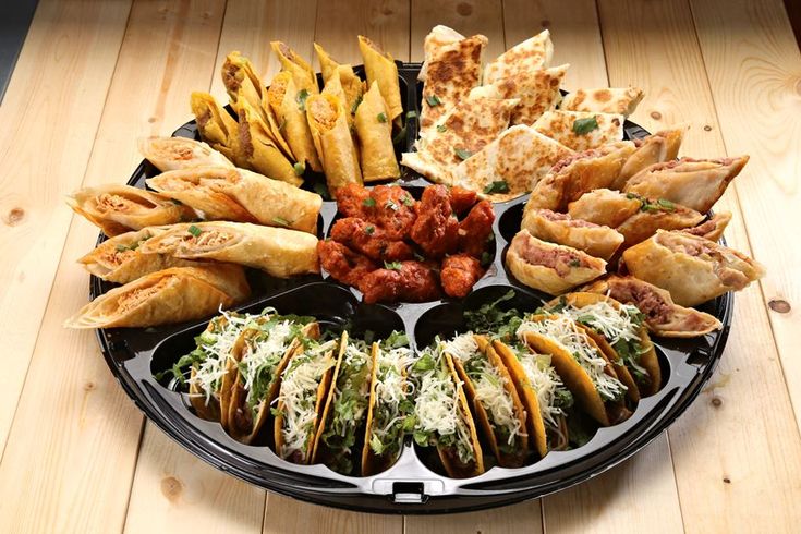 a platter filled with tacos, tortilla shells and other food items