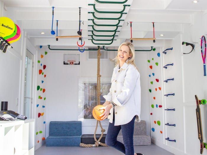 a woman standing in a room holding an orange ball and some other items hanging from the ceiling