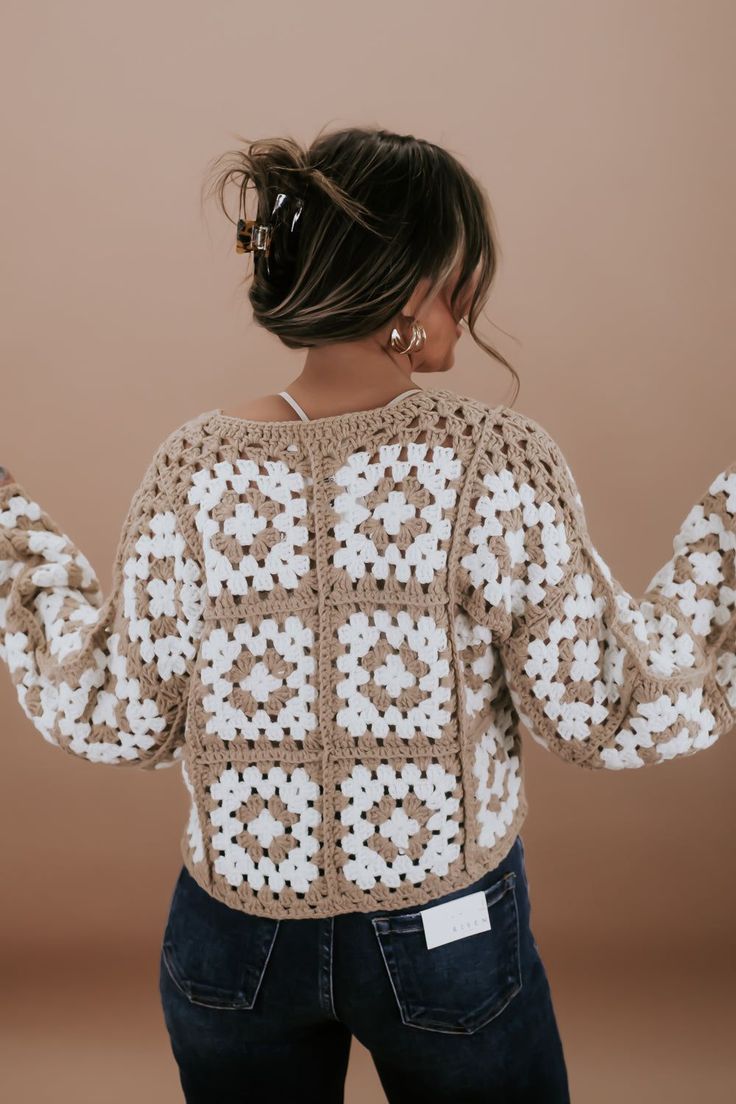 a woman with her back to the camera, wearing a crocheted sweater and jeans