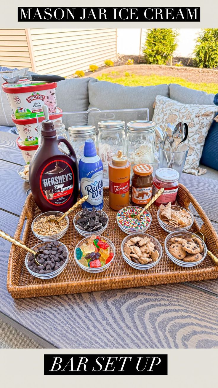 an outdoor table is set up with mason jar ice cream and desserts on it