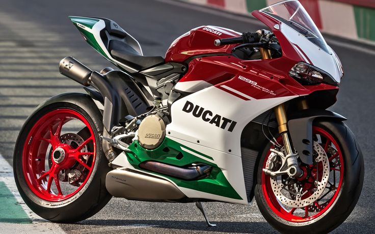 a red, white and green motorcycle parked on a race track