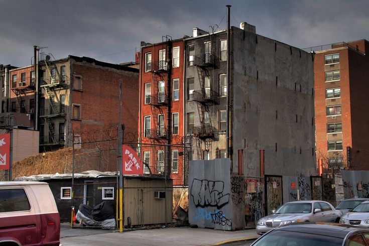 an old building with graffiti on it in the middle of a city street next to parked cars