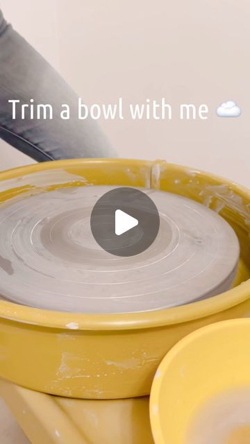 a person using a pottery wheel on a yellow bowl with the words trim a bowl with me