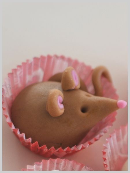 there is a chocolate mouse in the cupcake wrapper with pink icing on it