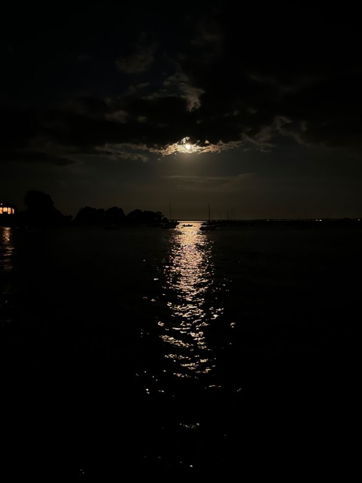 the moon is shining brightly over the water