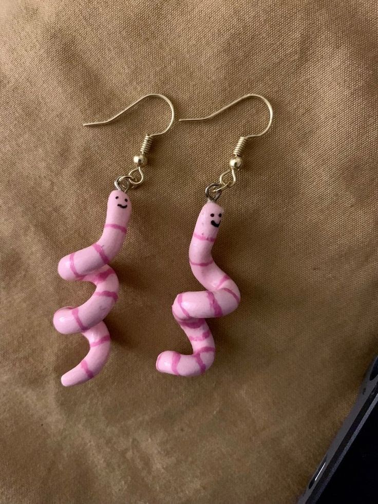 pink and white candy earrings with silver earwires on top of a brown cloth