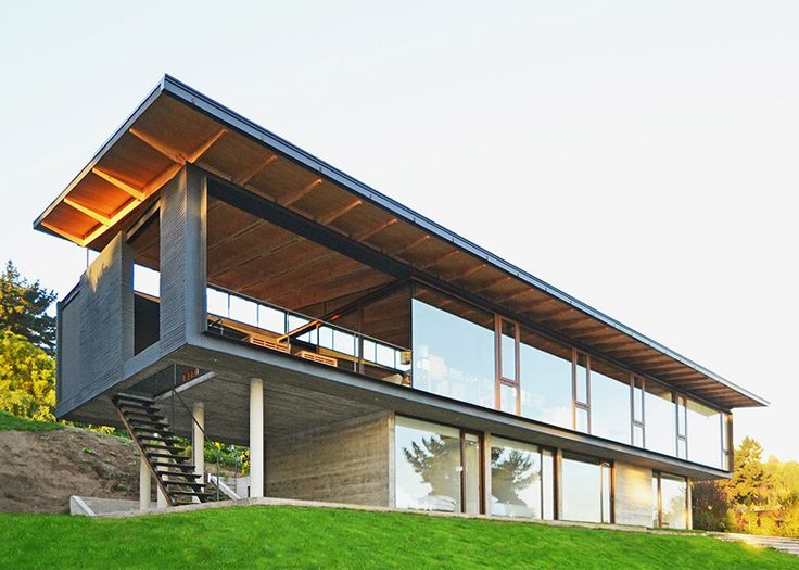 a modern house sitting on top of a lush green hillside