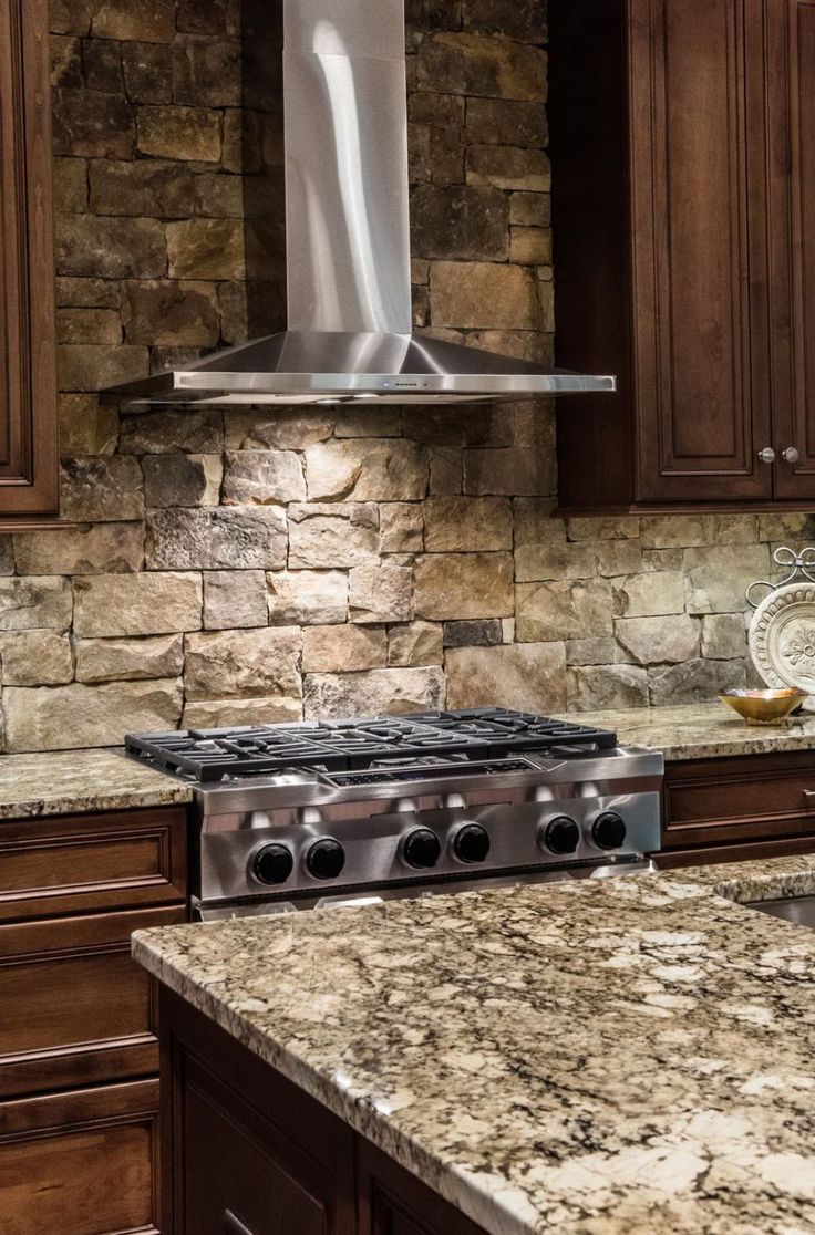 a stove top oven sitting inside of a kitchen next to wooden cabinets and granite counter tops