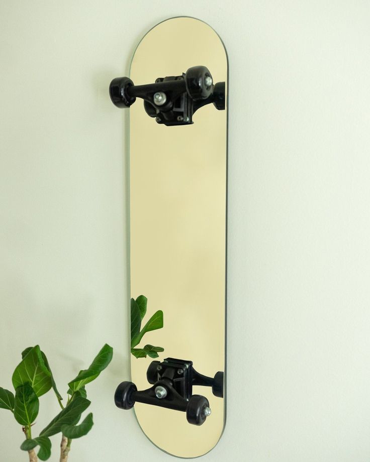 a skateboard mounted to the side of a wall next to a potted plant