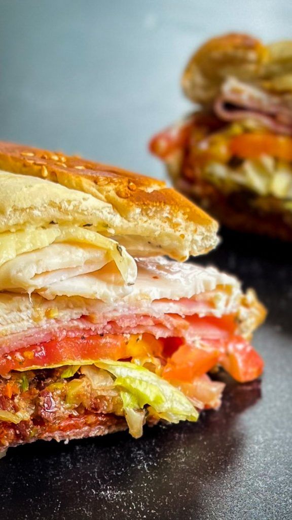 a sandwich cut in half sitting on top of a black table next to another sandwich