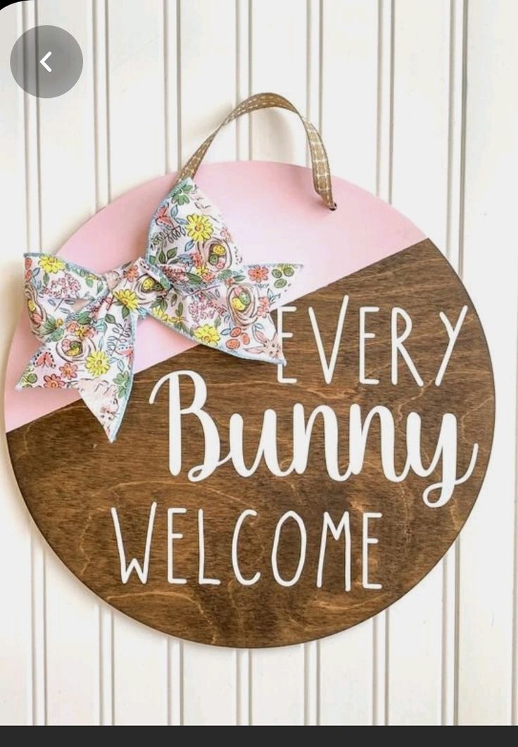 a wooden sign that says, every bunny welcome with a bow on the front door