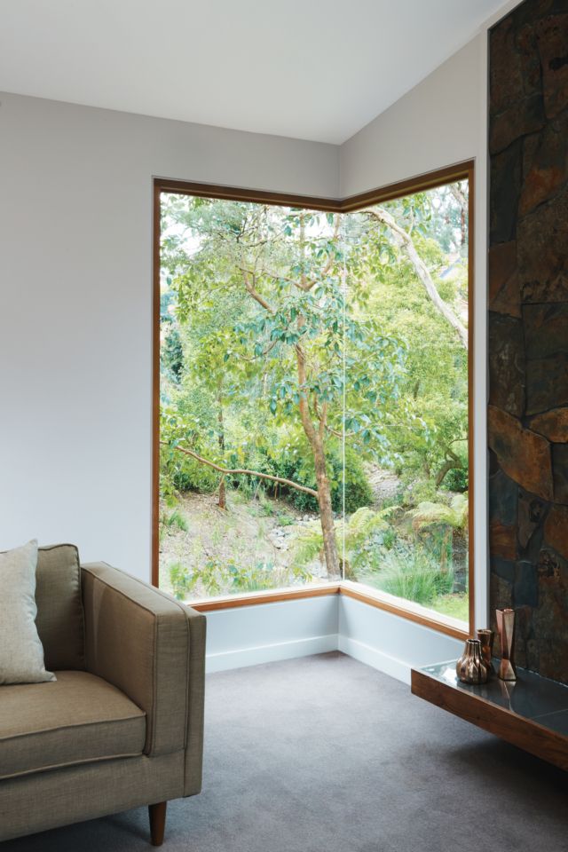 a living room filled with furniture and a large window that looks out onto the woods