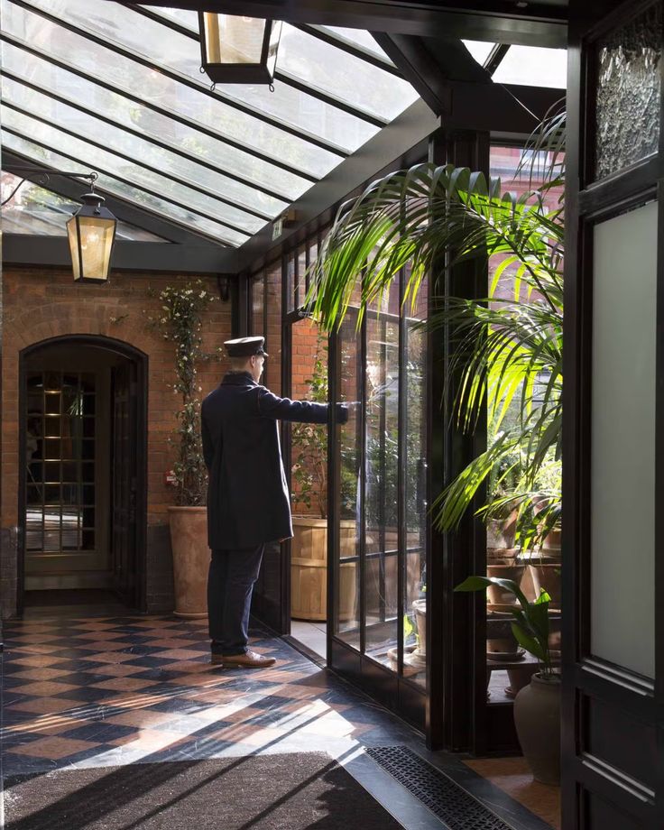 a man in a suit and hat is entering a building with glass doors on both sides