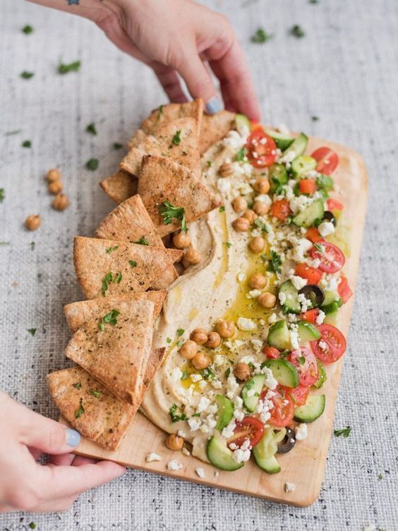 a person is holding a tortilla with vegetables and chickpeas on it