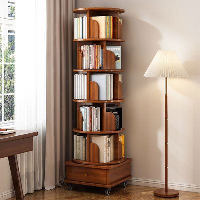 a room with a lamp, bookshelf and a table in it next to a window