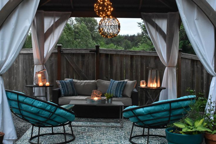 an outdoor living area with blue chairs and lights