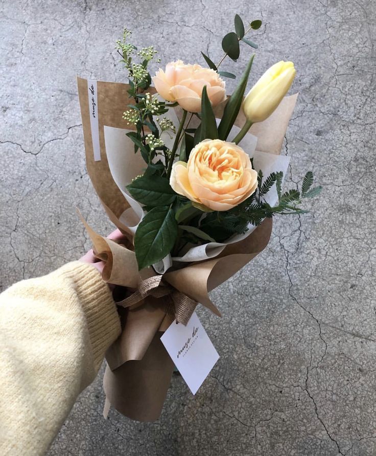 a person holding a bouquet of flowers in their hand on the ground with tags attached to it