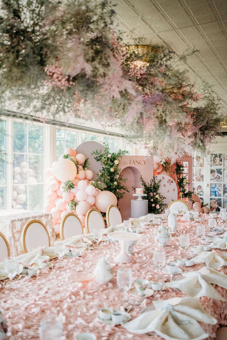 a table set up for a party with pink and white decorations