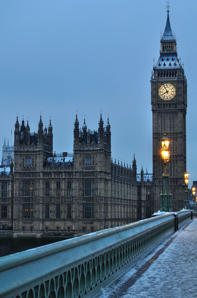 the big ben clock tower towering over the city of london in the winter time with snow on the ground