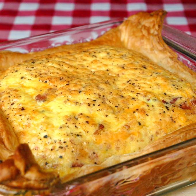 a cheesy casserole dish on a red and white checkered tablecloth