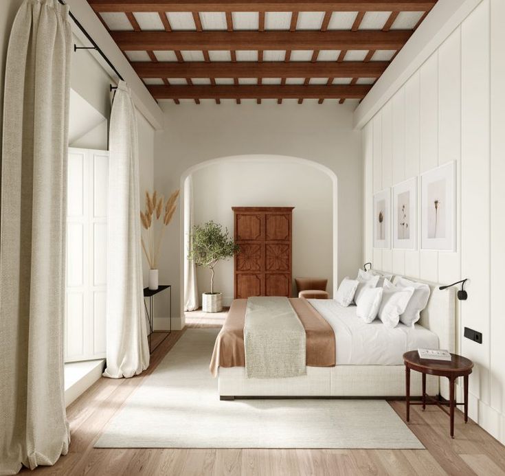 a bedroom with white walls and wood floors, along with a large bed in the center