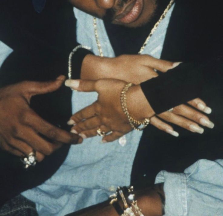 a man in a black jacket and some bracelets on his arm with two hands