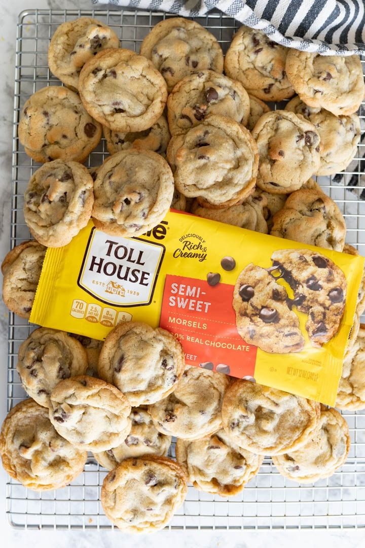 chocolate chip cookies on a cooling rack next to a bag of toll house