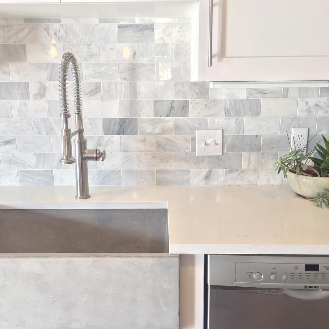 Clean modern luck with marble subway tile backsplash, and quartz countertops And a cement sink