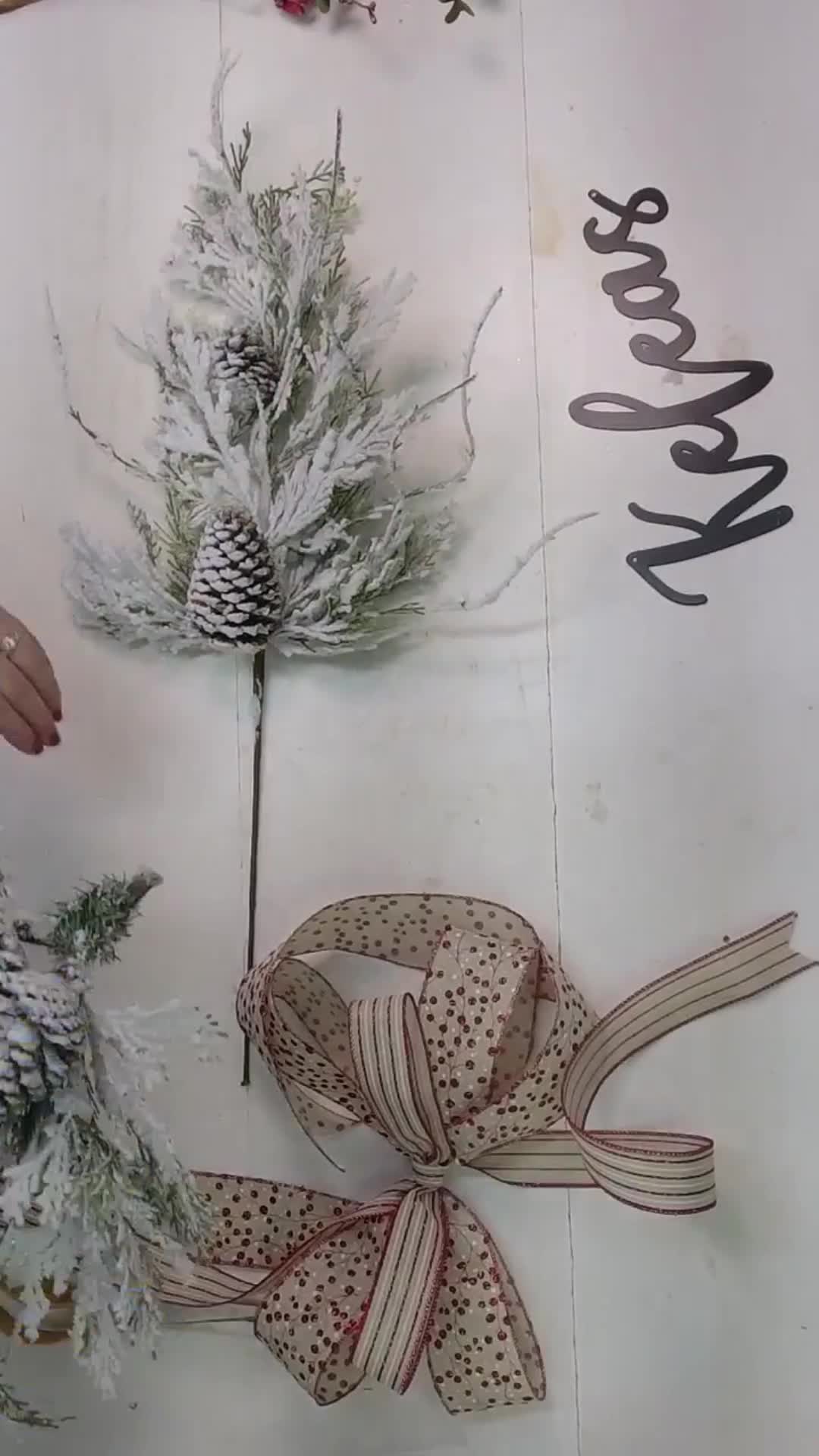 This may contain: a christmas decoration with pine cones and ribbons