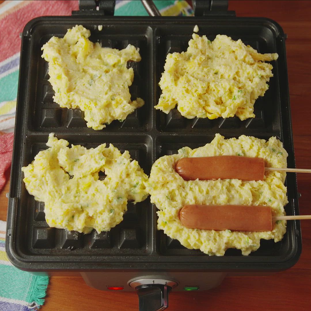 This may contain: hotdogs and scrambled eggs in a pan with toothpicks on the side