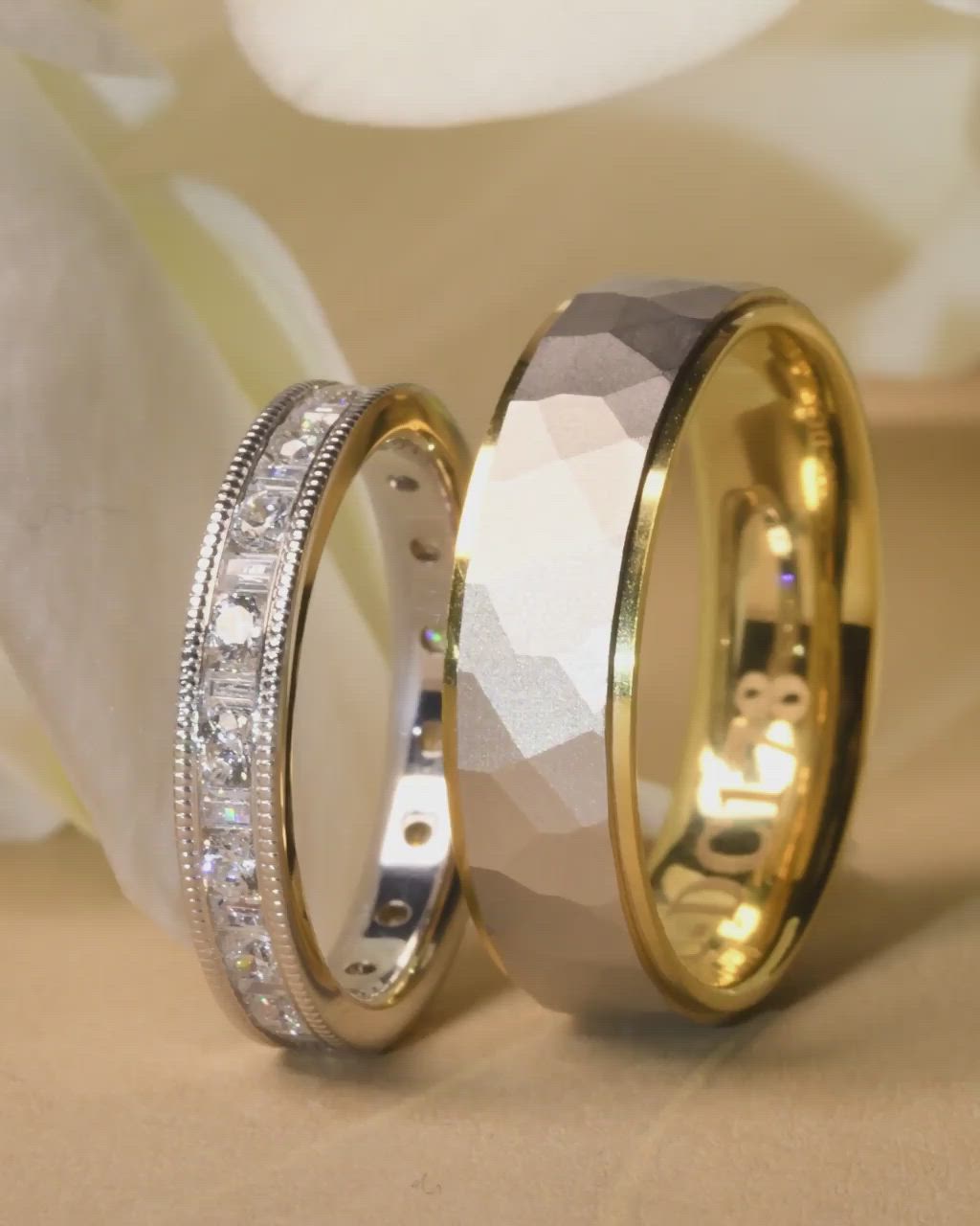 This may contain: two gold wedding bands with white diamonds on each side and in the middle, sitting next to each other