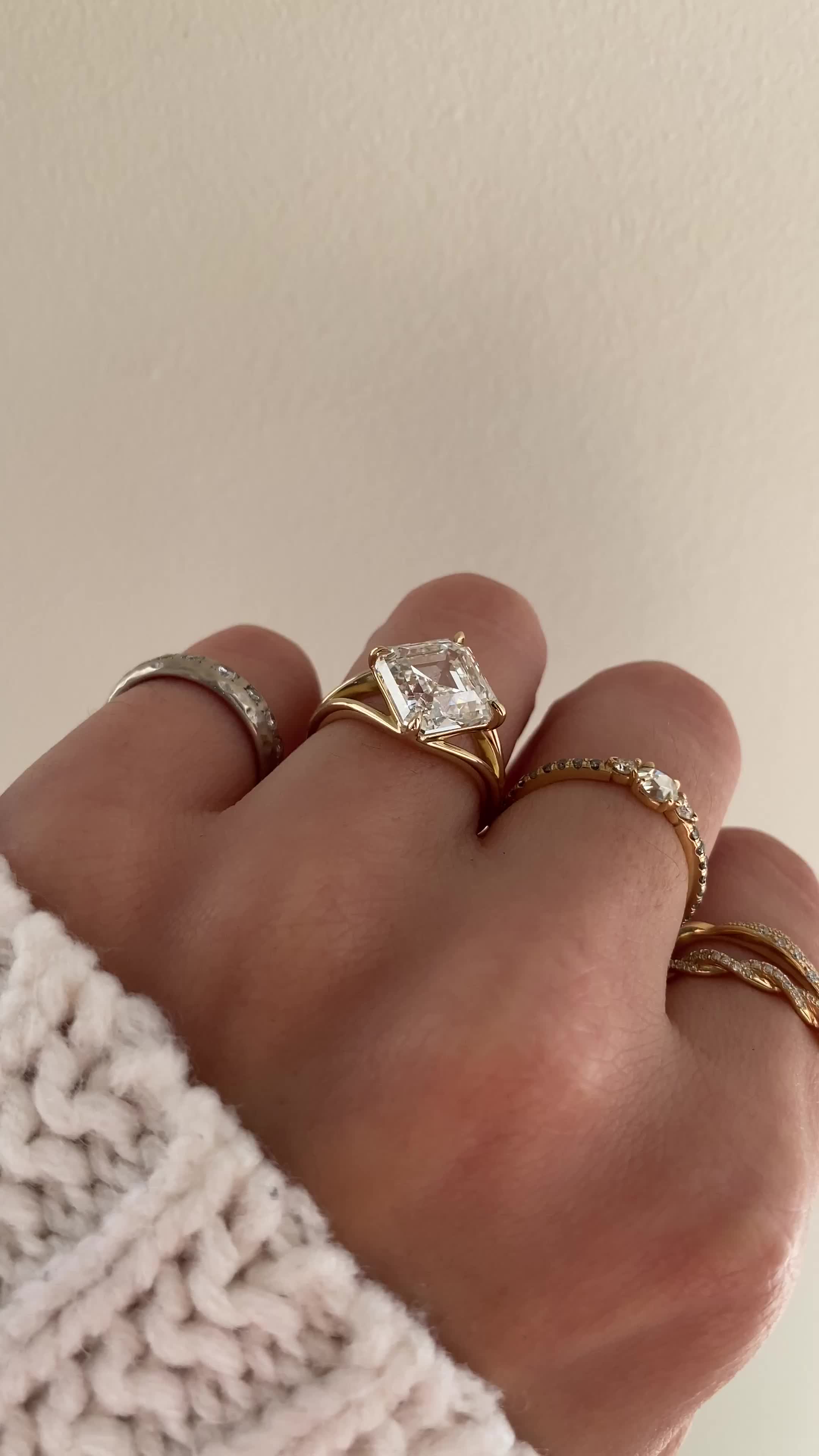 This may contain: a woman's hand with three different rings on it and one is wearing a sweater