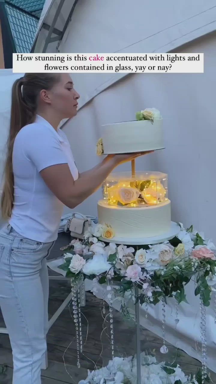 This may contain: a woman is decorating a cake with lights and flowers