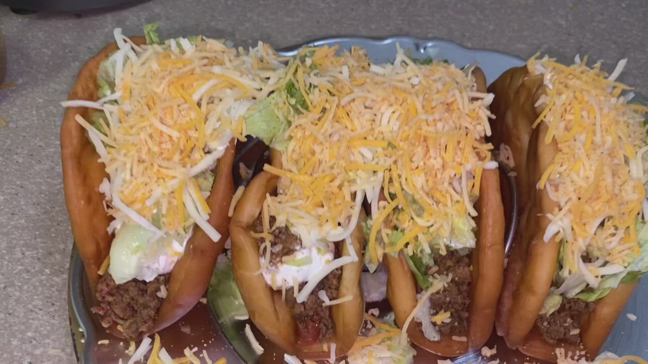 This may contain: three hot dogs covered in cheese and chili sitting on top of each other with buns