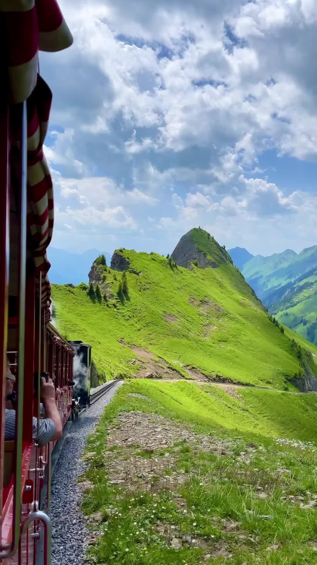 This may contain: a small house in the middle of a lush green field with mountains in the background